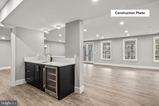 kitchen featuring light wood-type flooring, wine cooler, a healthy amount of sunlight, and sink