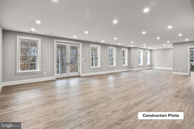 unfurnished living room featuring french doors, light hardwood / wood-style floors, and plenty of natural light