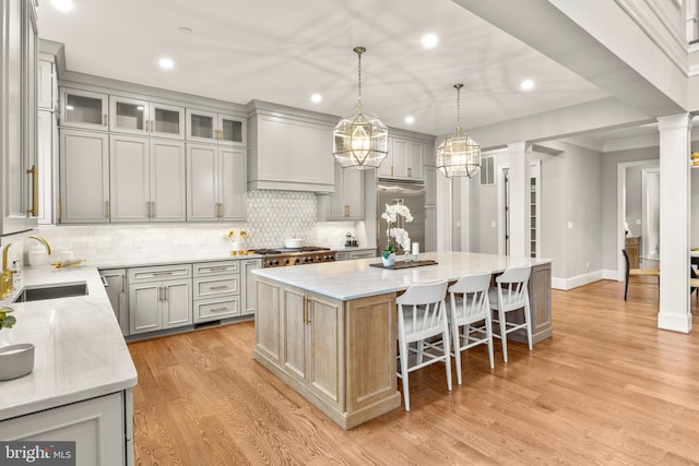 kitchen with crown molding, sink, pendant lighting, a center island, and light hardwood / wood-style floors