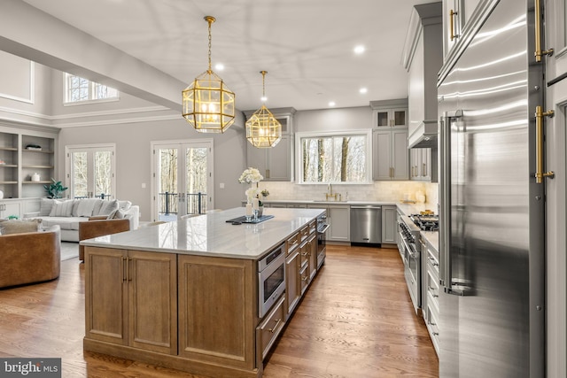 kitchen featuring light stone counters, high end appliances, hardwood / wood-style floors, a center island, and white cabinetry