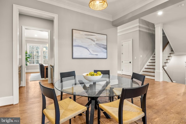 dining room with crown molding, light hardwood / wood-style floors, and an inviting chandelier