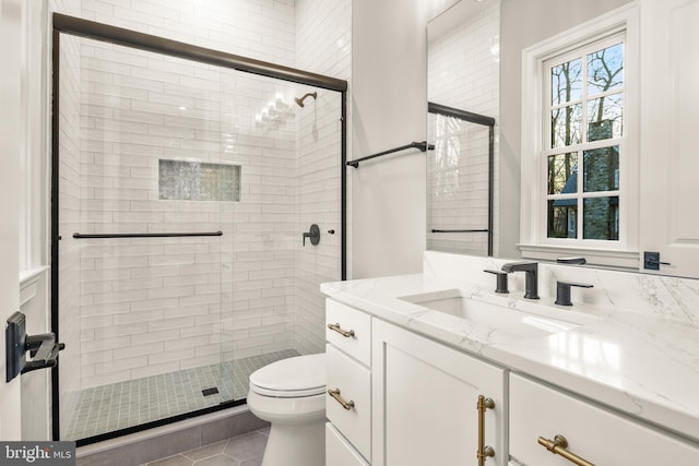 bathroom featuring tile patterned flooring, vanity, toilet, and a shower with shower door