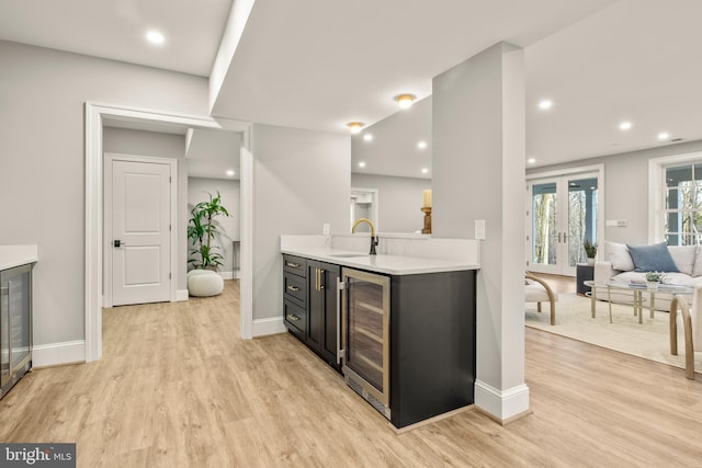 kitchen with sink, beverage cooler, french doors, and light hardwood / wood-style flooring