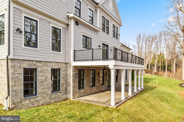 rear view of property with a yard, a patio area, and a balcony