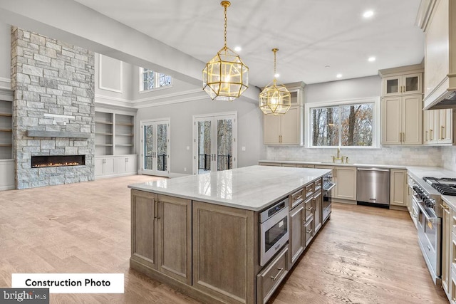 kitchen with pendant lighting, a center island, cream cabinets, a fireplace, and stainless steel appliances