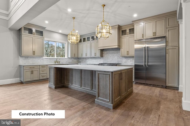 kitchen featuring a center island, built in fridge, hanging light fixtures, tasteful backsplash, and dark hardwood / wood-style flooring