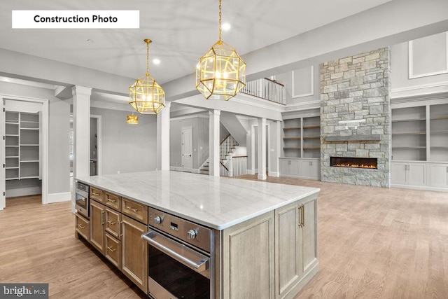 kitchen featuring a fireplace, a center island, pendant lighting, and light hardwood / wood-style floors