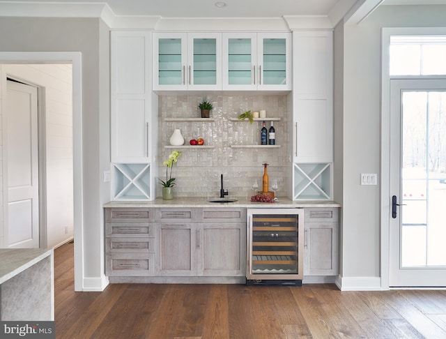 bar with dark wood-type flooring, white cabinets, decorative backsplash, and beverage cooler