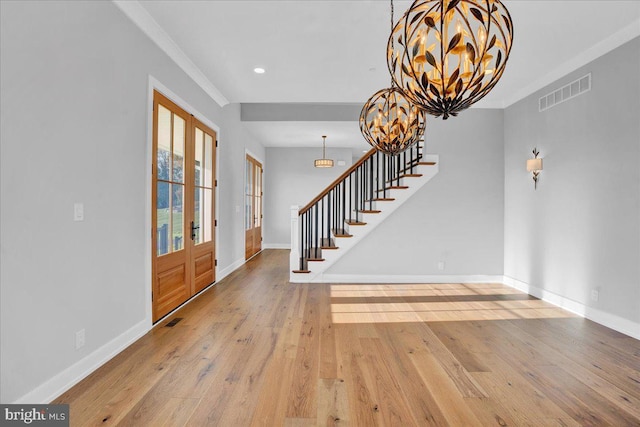 entrance foyer with light hardwood / wood-style floors, an inviting chandelier, and crown molding