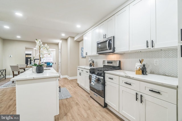 kitchen with a center island, appliances with stainless steel finishes, light wood-type flooring, and white cabinets