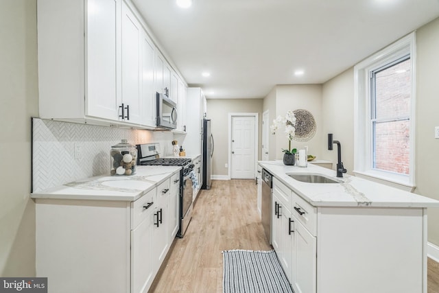 kitchen featuring appliances with stainless steel finishes, sink, white cabinetry, light stone counters, and light hardwood / wood-style flooring