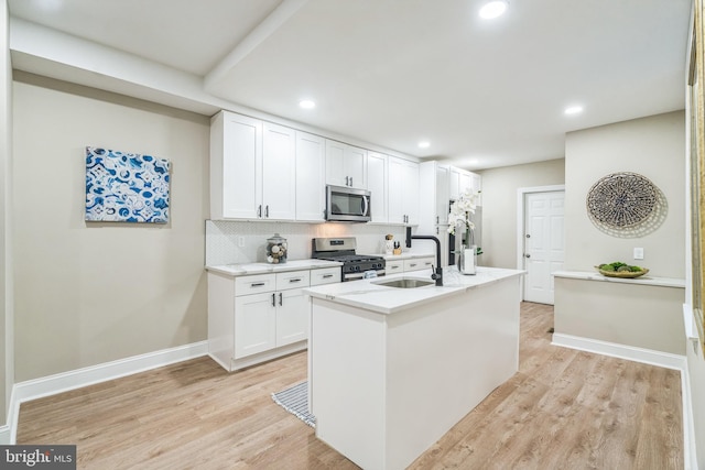 kitchen with white cabinetry, appliances with stainless steel finishes, sink, and an island with sink