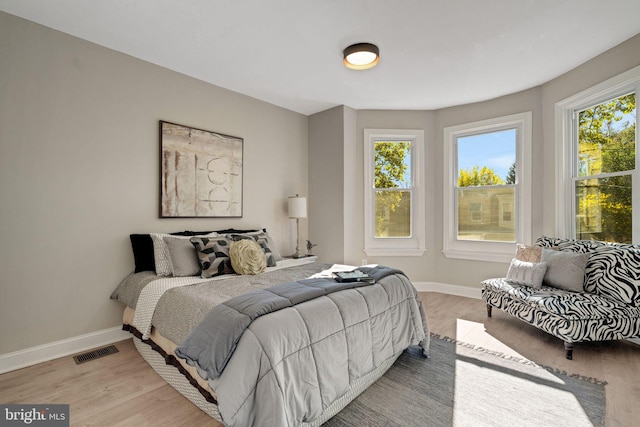 bedroom with multiple windows and light hardwood / wood-style floors