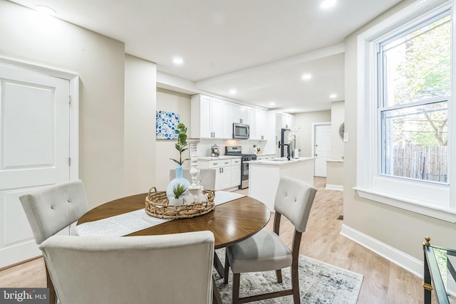 dining area with sink and light wood-type flooring