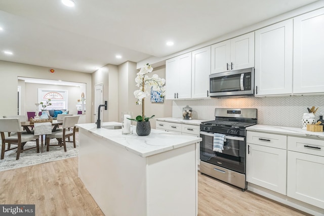 kitchen featuring white cabinetry, stainless steel appliances, and a kitchen island with sink