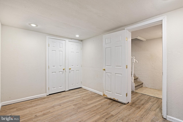 basement with light hardwood / wood-style flooring and a textured ceiling