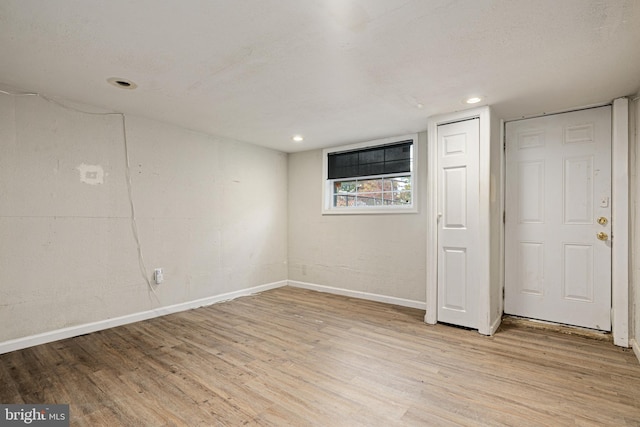 basement featuring a textured ceiling and light wood-type flooring