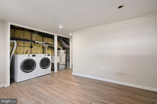 laundry room with gas water heater, washing machine and clothes dryer, and wood-type flooring