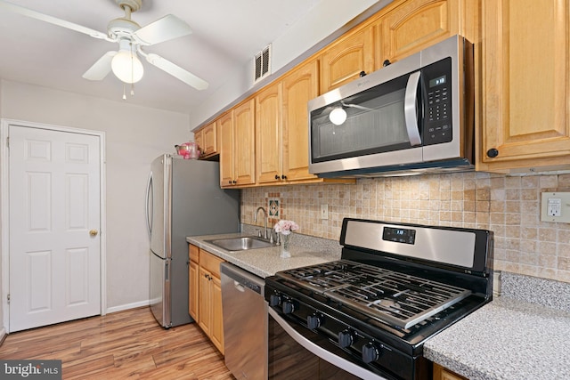 kitchen featuring decorative backsplash, ceiling fan, sink, light hardwood / wood-style floors, and stainless steel appliances