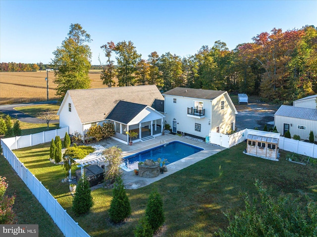 rear view of property with a patio, a storage shed, a lawn, and a fenced in pool