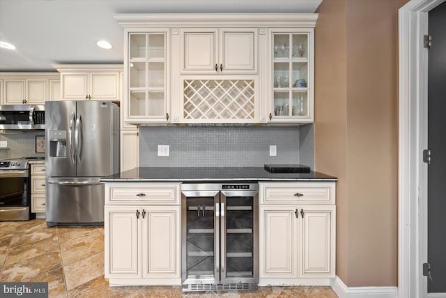 kitchen with wine cooler, decorative backsplash, appliances with stainless steel finishes, and cream cabinetry