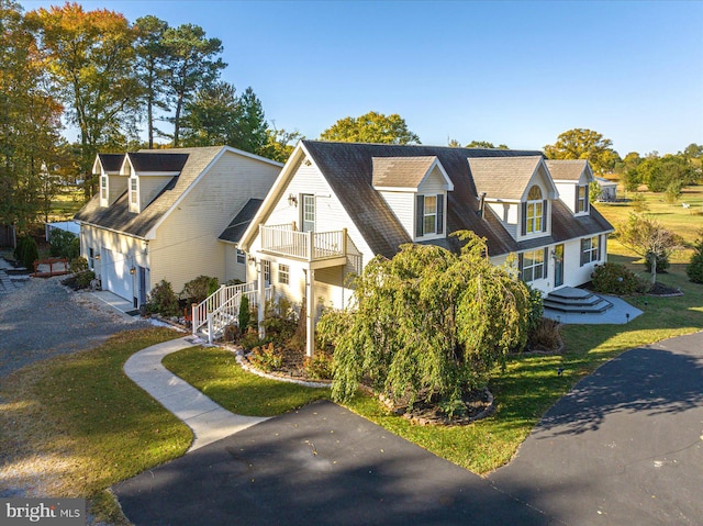 view of front of home featuring a front lawn, a garage, and a balcony