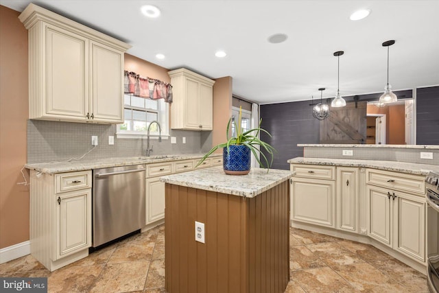 kitchen with light stone countertops, appliances with stainless steel finishes, cream cabinetry, a center island, and pendant lighting