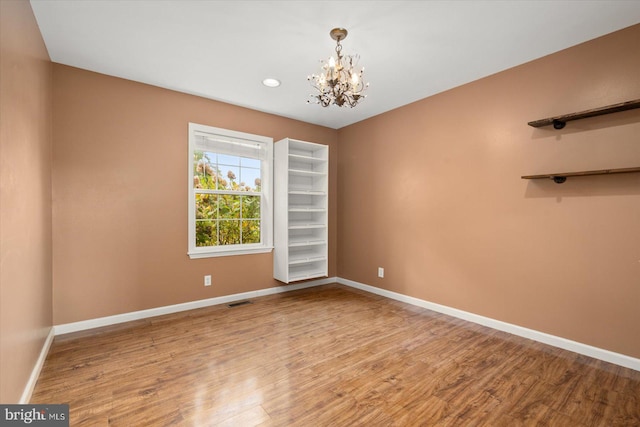 empty room featuring a chandelier and light hardwood / wood-style flooring