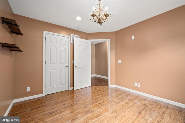 unfurnished bedroom with light hardwood / wood-style floors and a notable chandelier