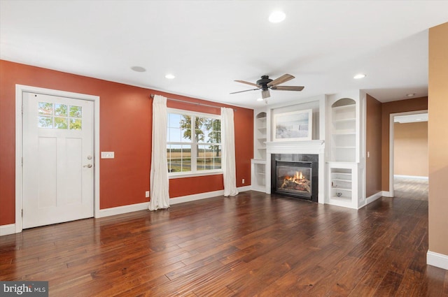 unfurnished living room with ceiling fan, built in features, and dark hardwood / wood-style flooring