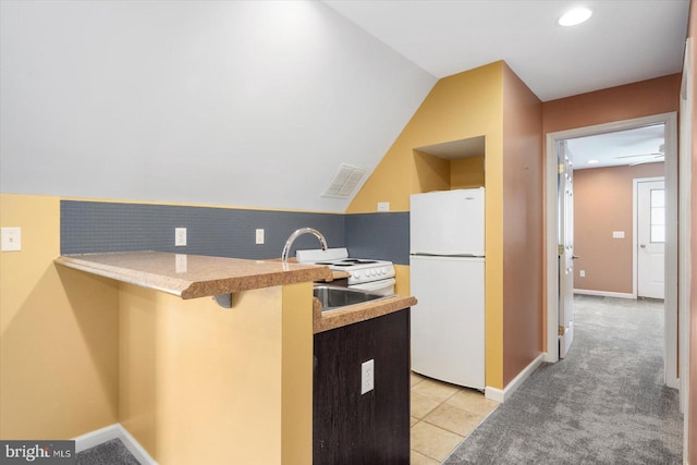 kitchen with white appliances, kitchen peninsula, lofted ceiling, a breakfast bar, and light colored carpet