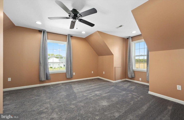 additional living space featuring ceiling fan, lofted ceiling, a wealth of natural light, and dark carpet