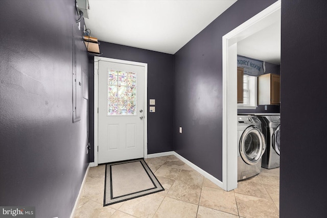 clothes washing area featuring washer and dryer, light tile patterned floors, and cabinets