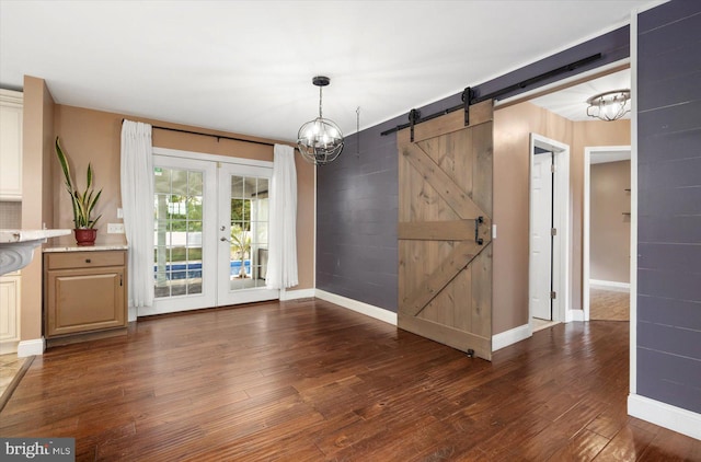 unfurnished dining area featuring french doors, dark hardwood / wood-style floors, and a barn door