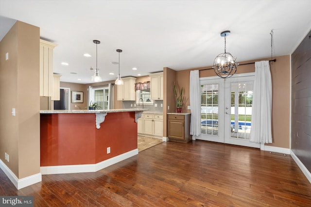 kitchen featuring french doors, cream cabinets, hardwood / wood-style floors, a breakfast bar, and pendant lighting