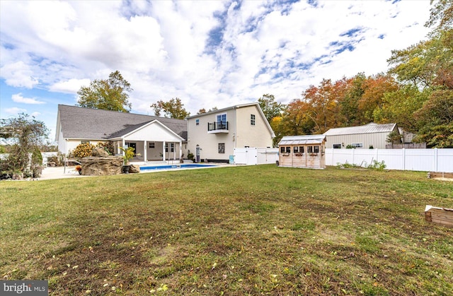 rear view of property featuring an outdoor structure, a lawn, and a fenced in pool