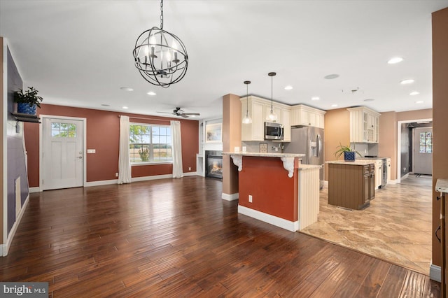 kitchen with stainless steel appliances, dark hardwood / wood-style flooring, a kitchen bar, and decorative light fixtures