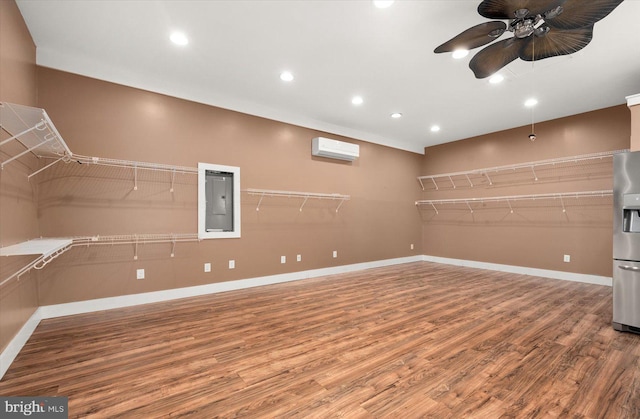 interior space featuring electric panel, a wall mounted AC, hardwood / wood-style flooring, and ceiling fan