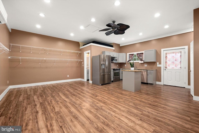 kitchen with gray cabinetry, wood-type flooring, a kitchen island, ceiling fan, and stainless steel appliances