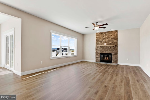 unfurnished living room featuring a fireplace, wood finished floors, baseboards, and ceiling fan