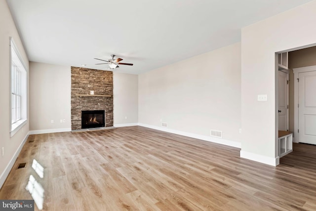 unfurnished living room featuring a stone fireplace, light hardwood / wood-style flooring, and ceiling fan