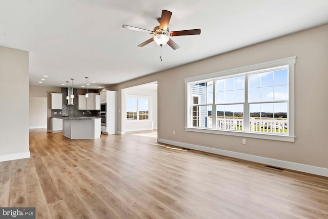 unfurnished living room with recessed lighting, visible vents, a ceiling fan, baseboards, and light wood-style flooring