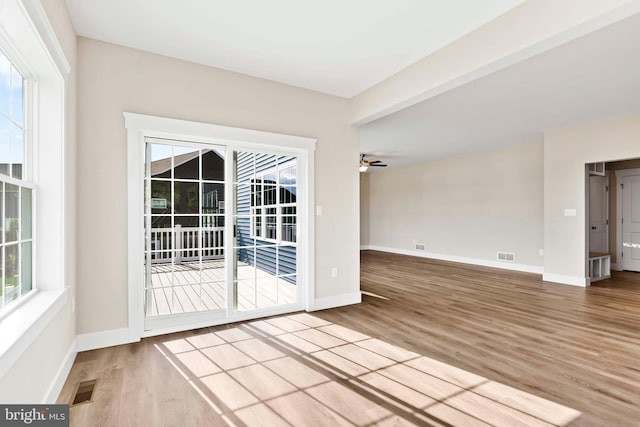 empty room with a ceiling fan, wood finished floors, and plenty of natural light