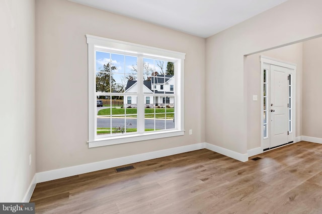 foyer entrance featuring baseboards, wood finished floors, and visible vents