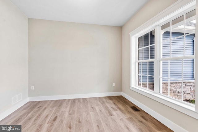 unfurnished room with baseboards, wood finished floors, and visible vents