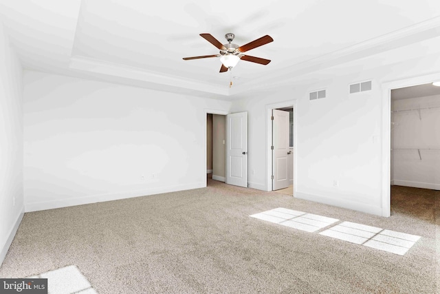 unfurnished bedroom with a raised ceiling, visible vents, carpet flooring, and a spacious closet