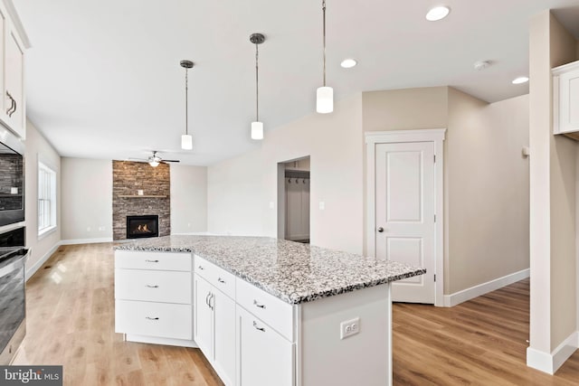 kitchen featuring ceiling fan, baseboards, oven, and light wood-style flooring