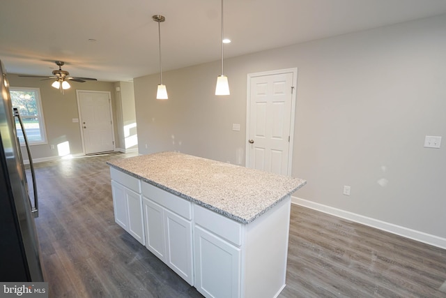 kitchen featuring dark hardwood / wood-style flooring, white cabinetry, ceiling fan, pendant lighting, and light stone counters