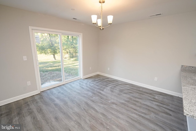 spare room featuring an inviting chandelier and dark wood-type flooring