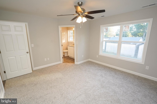 unfurnished bedroom with light carpet, ensuite bathroom, and ceiling fan